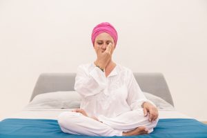 donna su letto che esegue una tecnica di meditazione per rilassarsi respirando alternando le narici